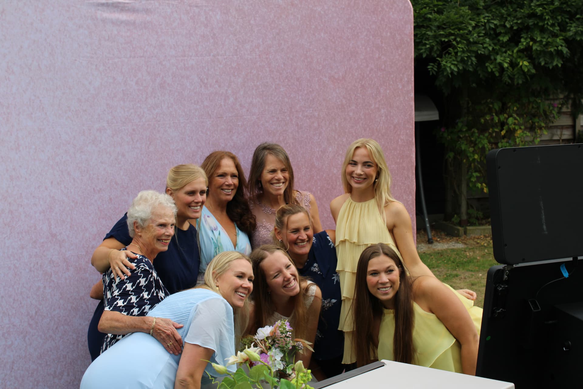 Lachende bruiloftsgasten voor de photobooth met roze achtergrond